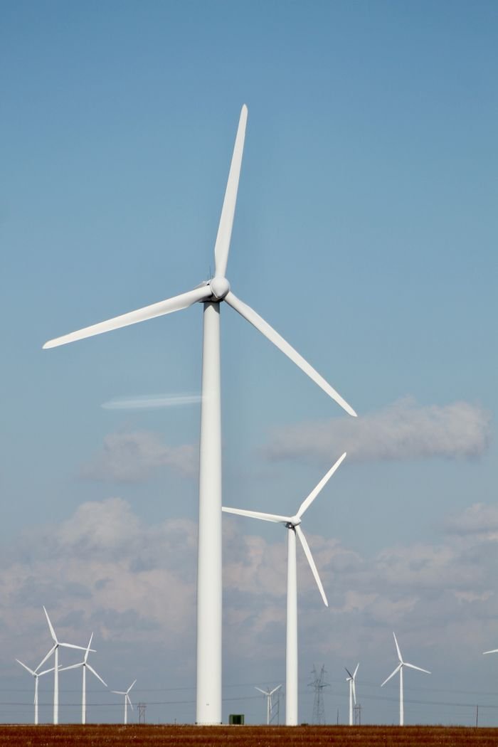 A series of tall wind turbines generating renewable energy in a clear open field.